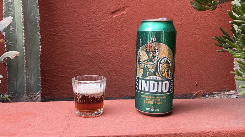 A can sitting next to a glass of Indio beer