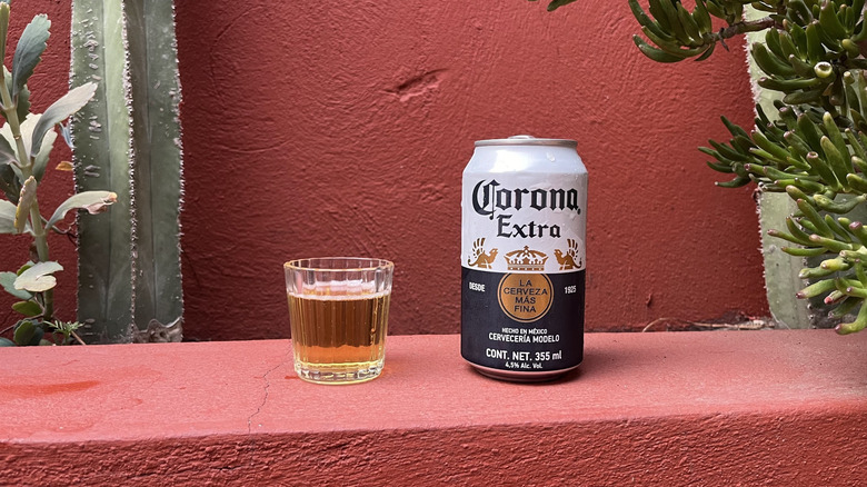 A can of Corona Extra sitting next to a filled glass