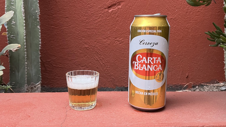 A can of Carta Blanca beer sitting next to a glass of it