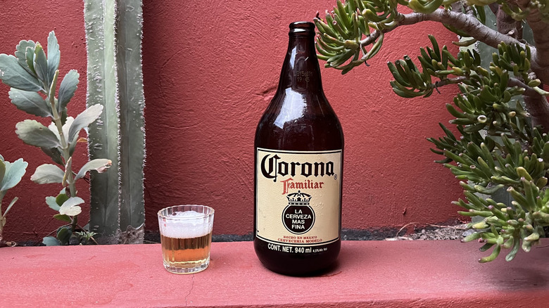 A bottle of Corona Familiar beer sitting next to a glass of it