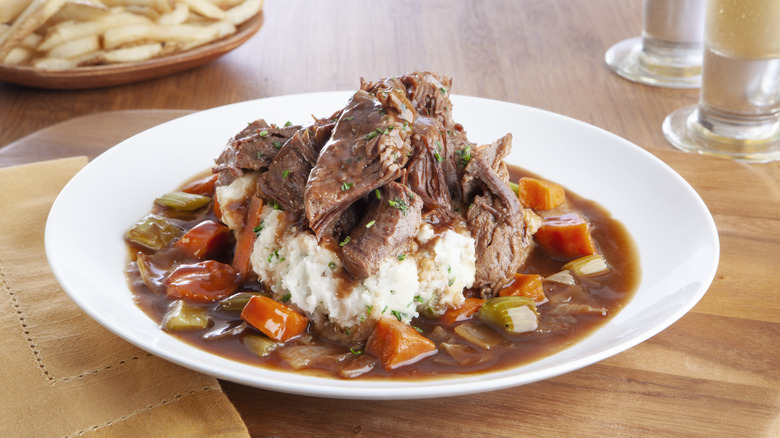 Classic pot roast with vegetables and herbs on a plate