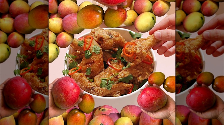 mangos surrounding bucket of Tam Tam wings on pink background