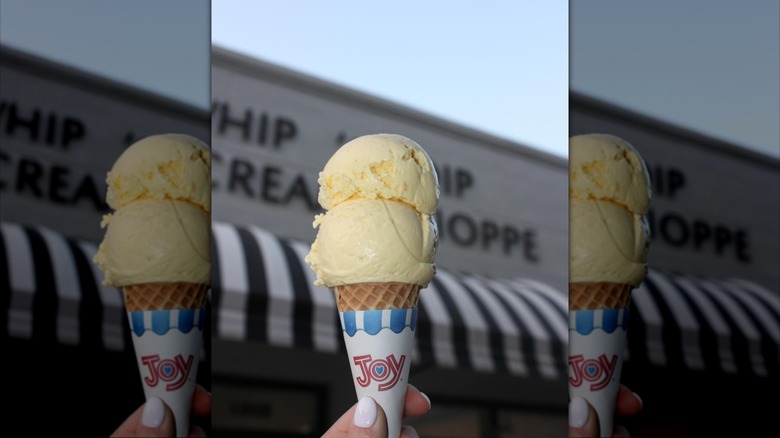 hand holding mango ice cream cone in front of Whip 'n Dip