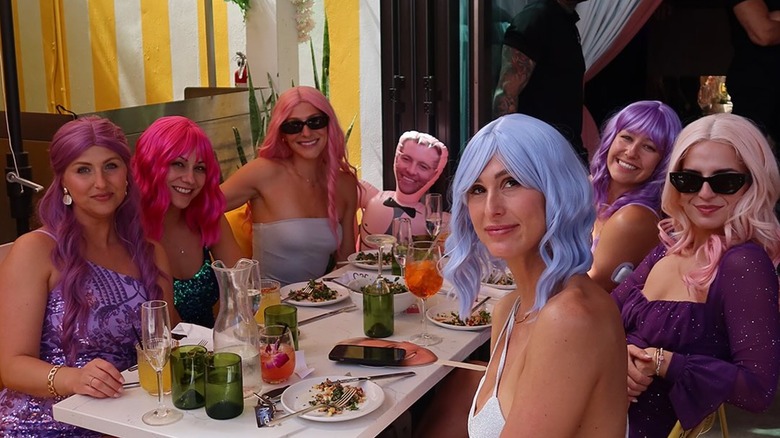 People eating at R House Wynwood wearing brightly-colored wigs