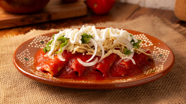 enchiladas covered in red sauce and cheese with sour cream