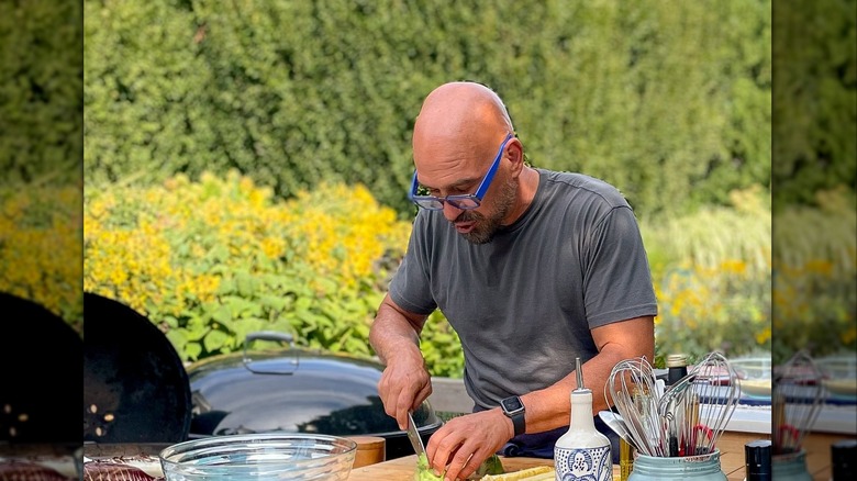 Michael Symon chopping ingredient in outdoor kitchen