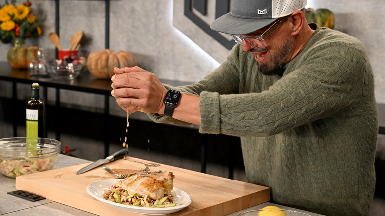 Michael Symon squeezing citrus onto a cooked piece of chicken