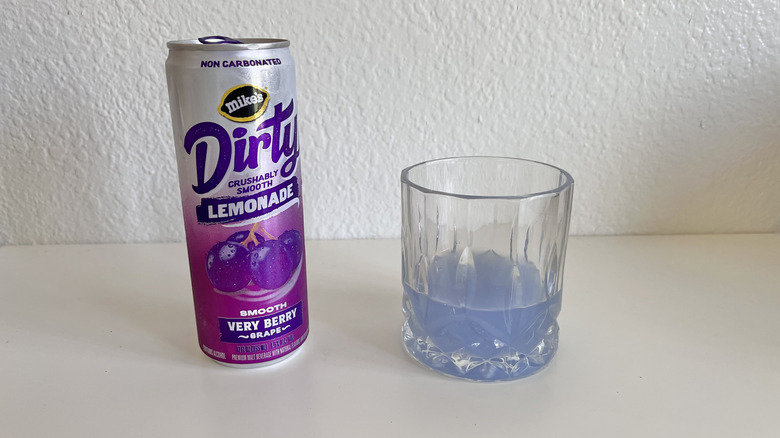 Dirty Lemonade Very Berry Grape can on a table next to a glass