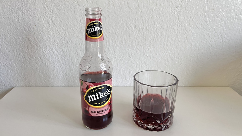 Hard Black Cherry bottle on a table next to a glass