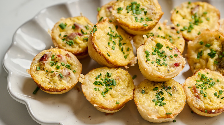 quiche cups on a platter topped with chives
