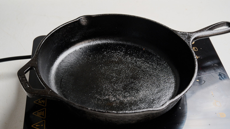 heating up a cast iron skillet over stove