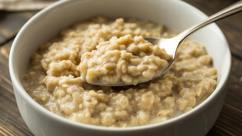a bowl of plain oatmeal in white bowl on wooden background