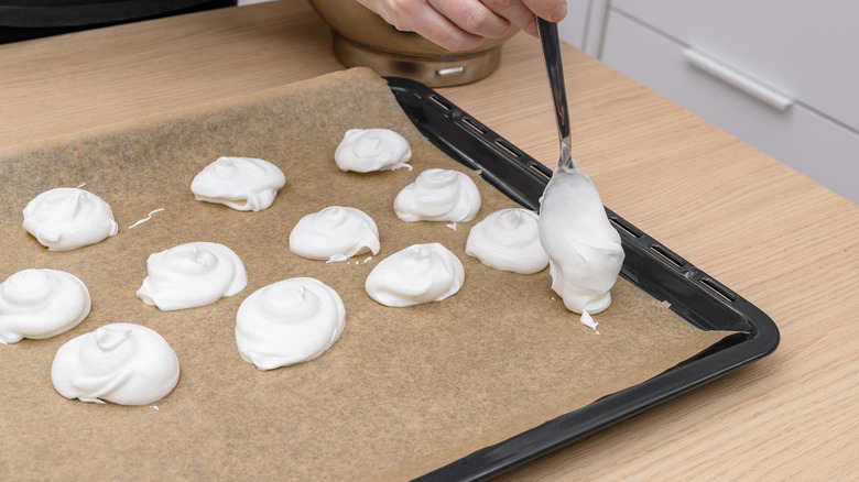 Spoon dropping meringue on parchment paper