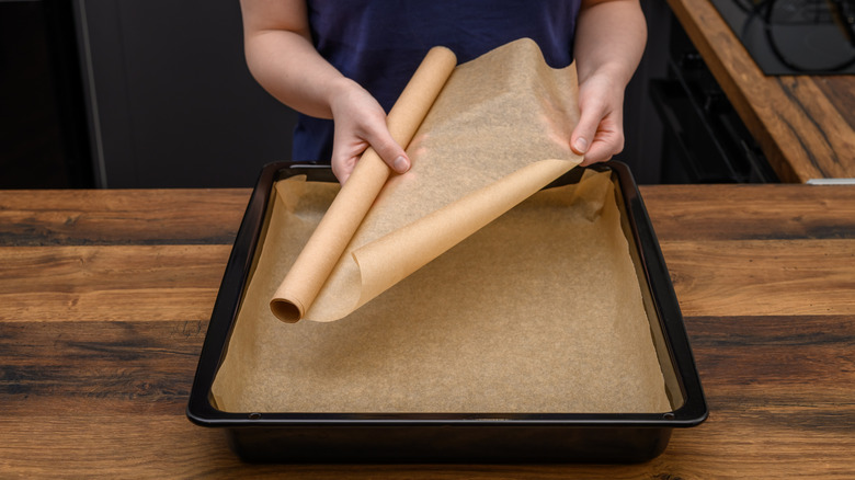 woman lining sheet tray with brown wax paper