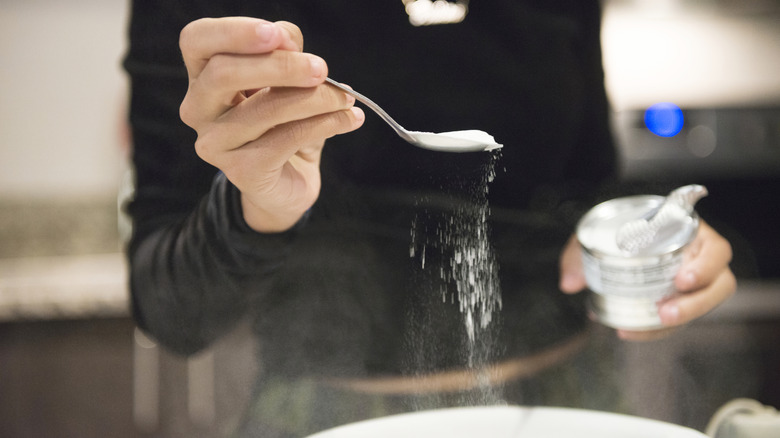 woman adding baking soda to bowl