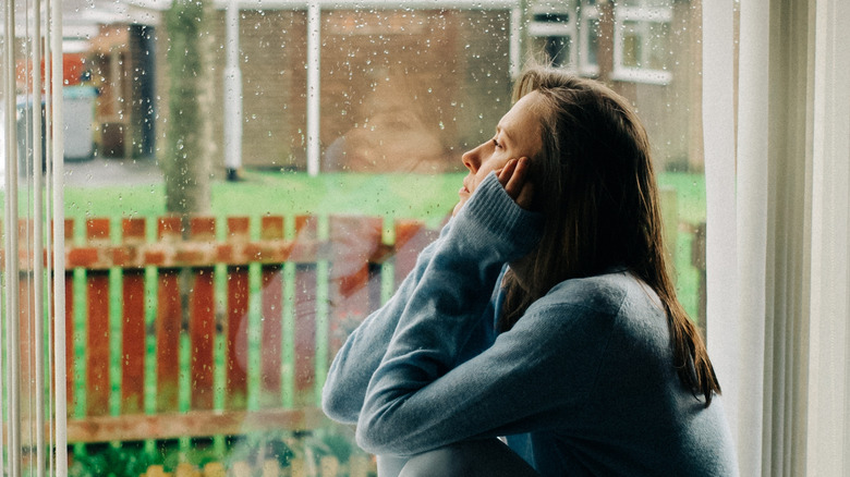thoughtful woman looking out the window at rainy weather
