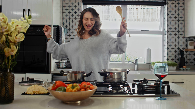 woman with arms up at the stove