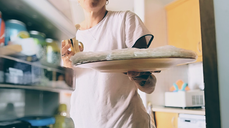 woman putting tray in refrigerator