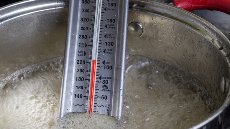 candy thermometer measuring temperature of bubbling sugar syrup