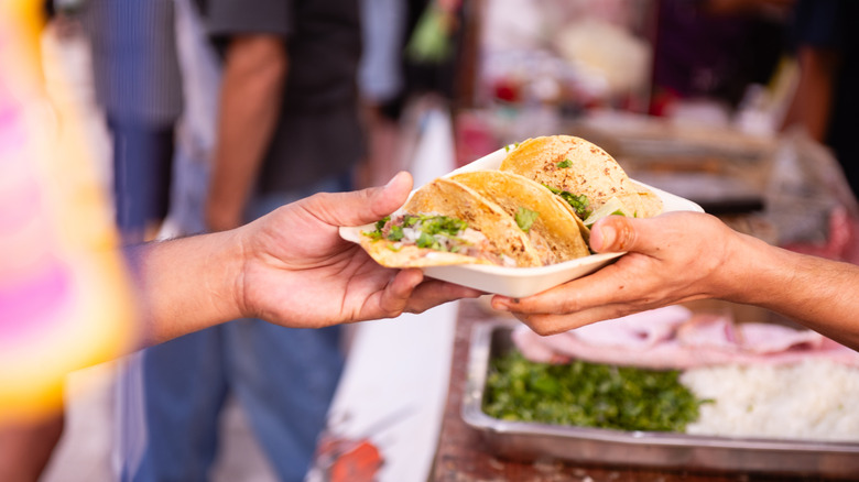 Woman handing mexican food to another person