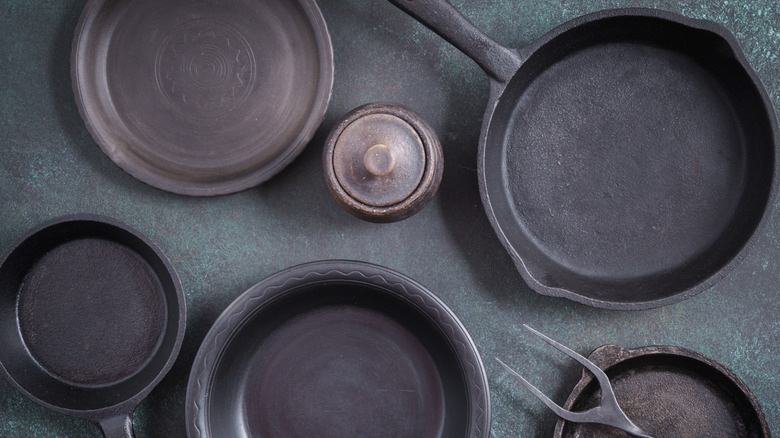 Cast-iron pans and a couple of ceramic dishes seen in an overhead view on a gray-green countertop
