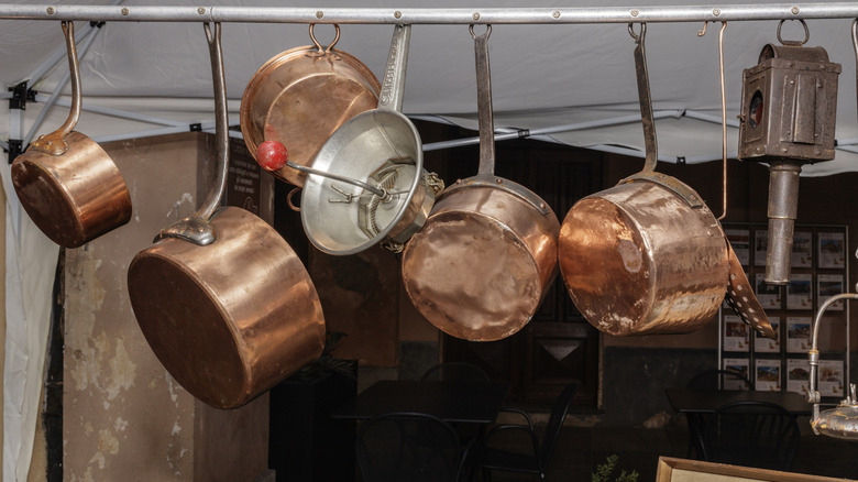 Vintage copper pots hanging from a rail in an antique shop