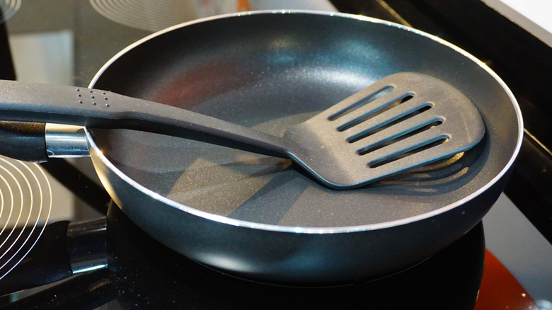 Non-stick skillet on a glass stovetop, with a nylon spatula resting in the pan