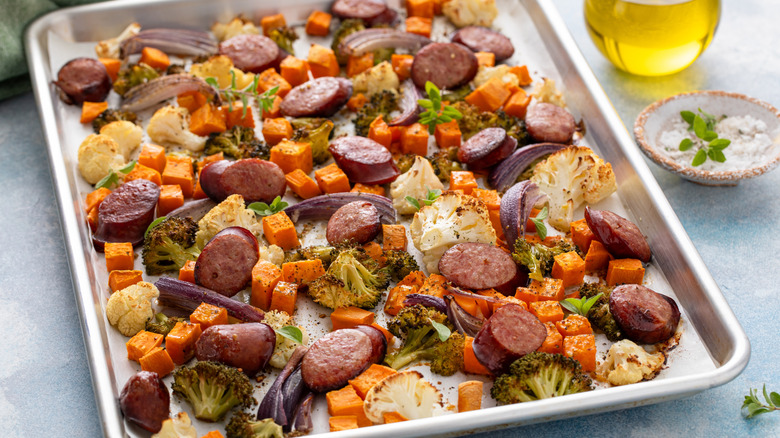 Sheet-pan meal consisting of roasted sausage and vegetables, all well-browned but not burnt and sprinkled with fresh herbs