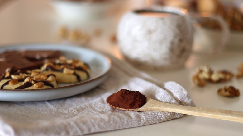 cocoa powder in spoon next to peanut butter cookie