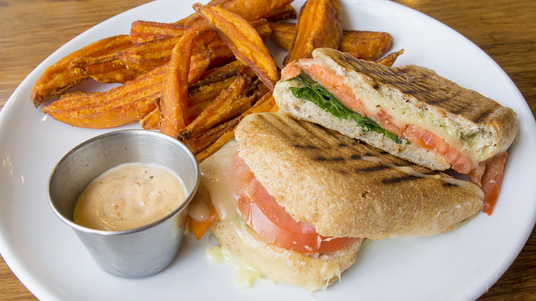 Overhead view of pesto grilled cheese with tomato and greens on a plate