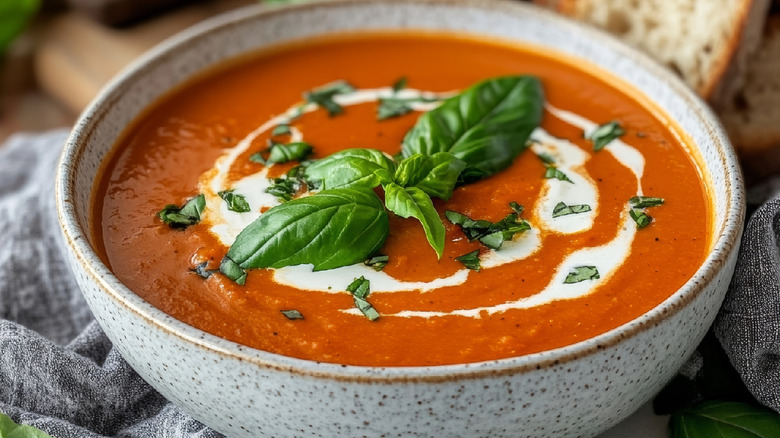 Closeup view of tomato soup in a bowl with fresh herbs