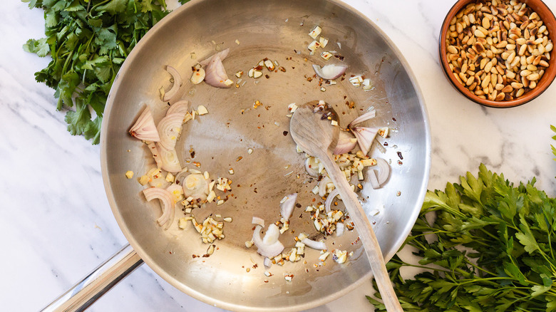 Garlic, chile, shallots and wooden spoon in a pan.