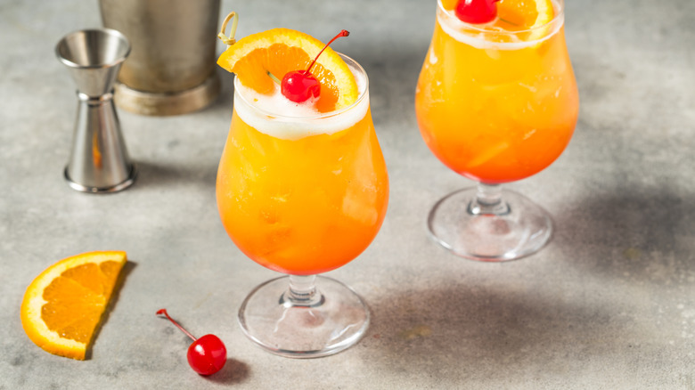 Two rum and orange juice cocktails garnished with maraschino cherries