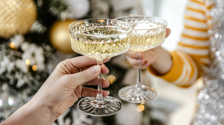 two people clinking crystal coupe glasses full of champagne