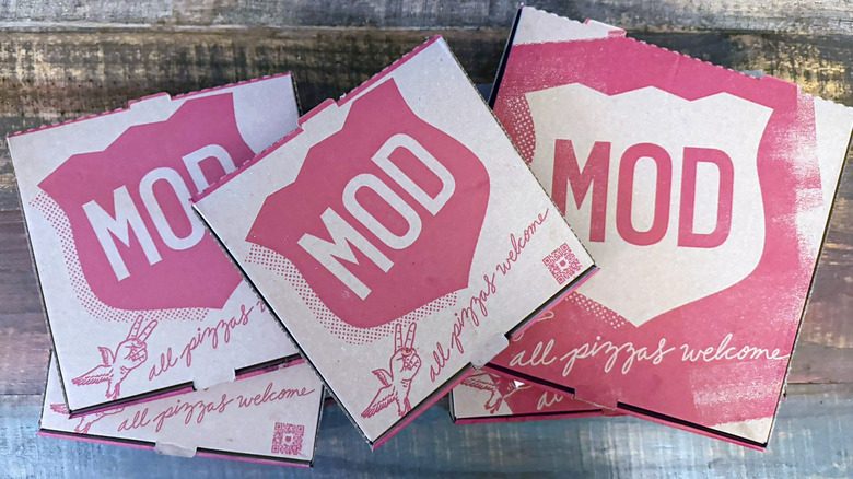Several MOD Pizza boxes on a table