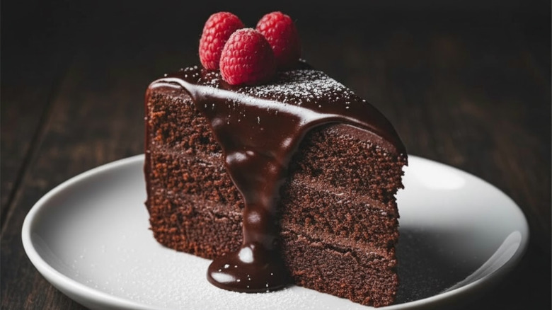 Slice of moist chocolate cake topped with raspberries.