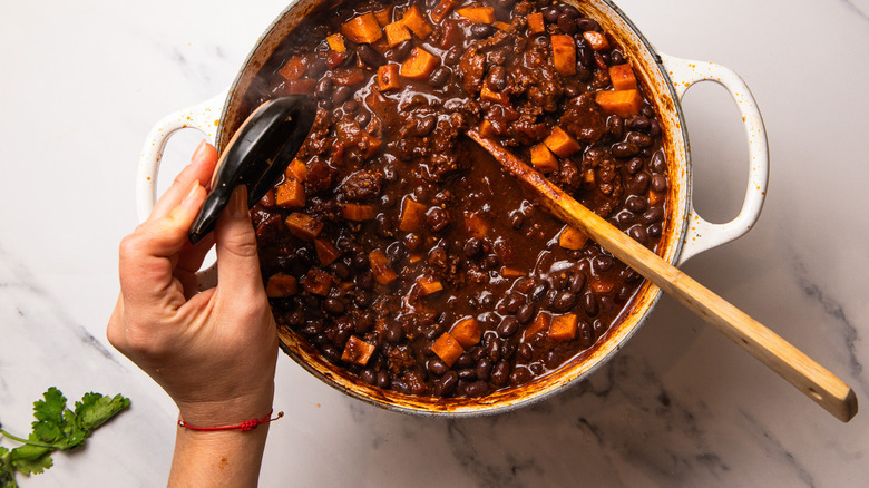 Adding spices to mole turkey chile cooking in Dutch oven