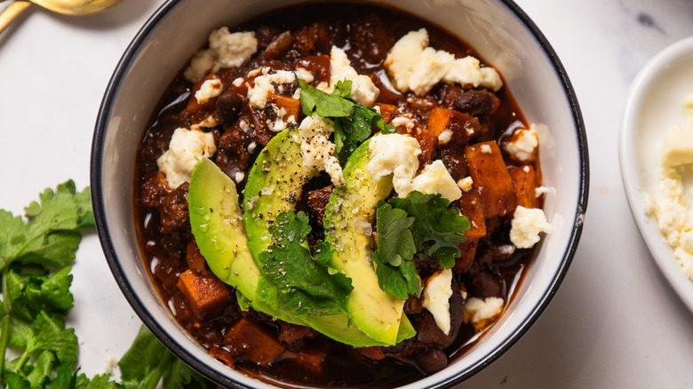 A garnished bowl of mole turkey and sweet potato chili