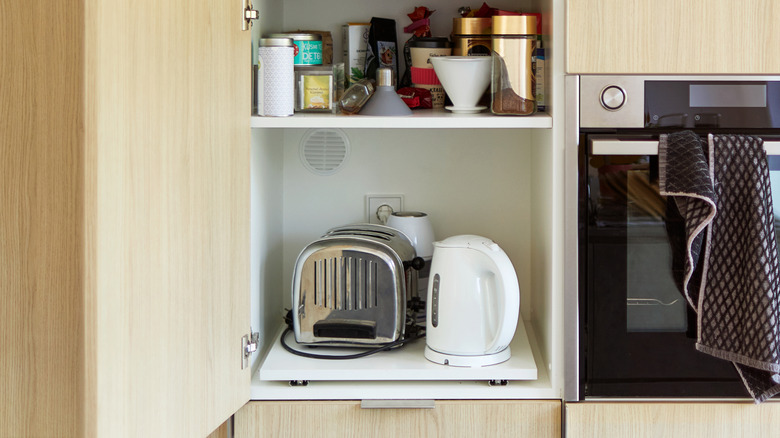 Cupboard full of kitchen appliances including a toaster
