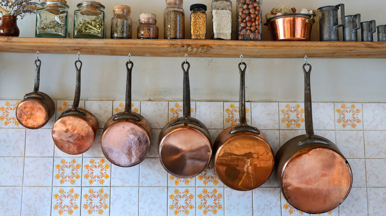 Copper pots hanging against tile backsplash