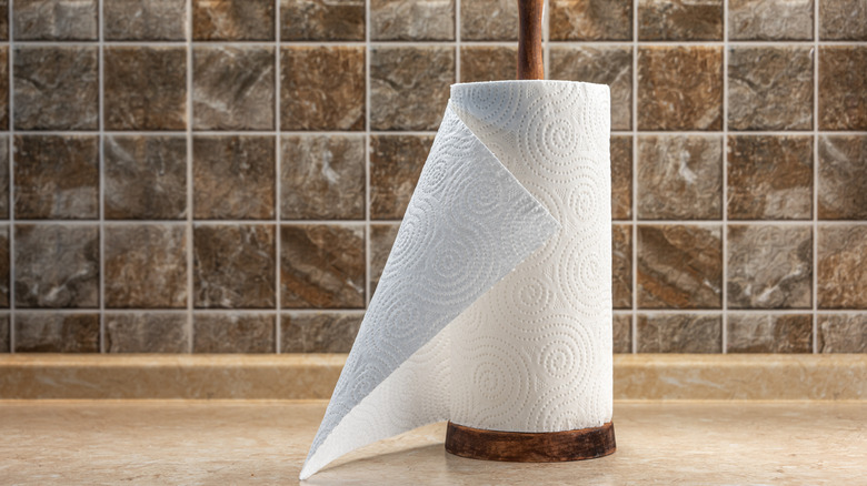 Paper towel roll on a wooden stand against kitchen backsplash