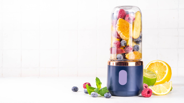 Mini one-cup blender filled with fruits and berries