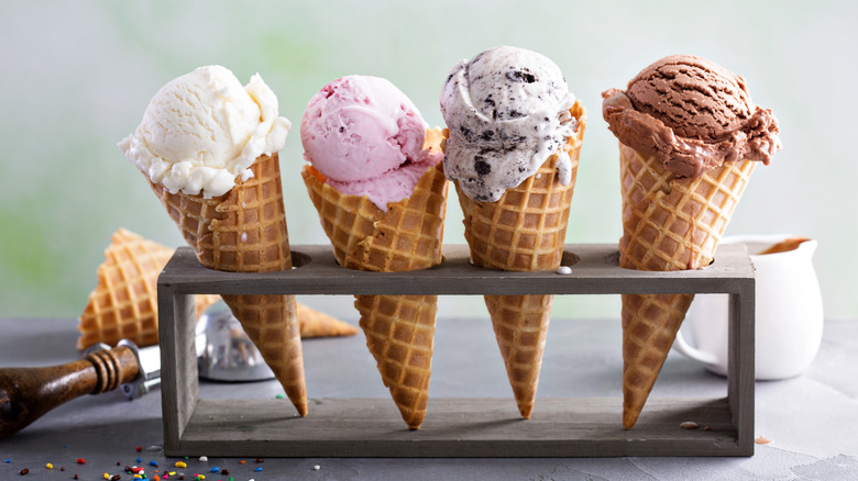 Scoops of different ice cream flavors in waffle cones in an ice cream cone display