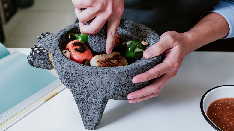 Man's hands using an authentic molcajete