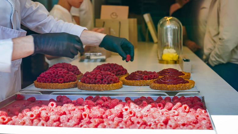 A chef topping raspberry tarts at Cedric Grolet