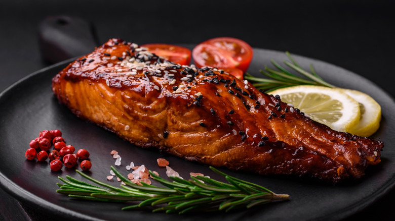 A piece of grilled salmon with a caramelized barbecue sauce and vegetables