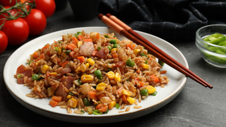 A cook tosses golden fried rice in a pan.