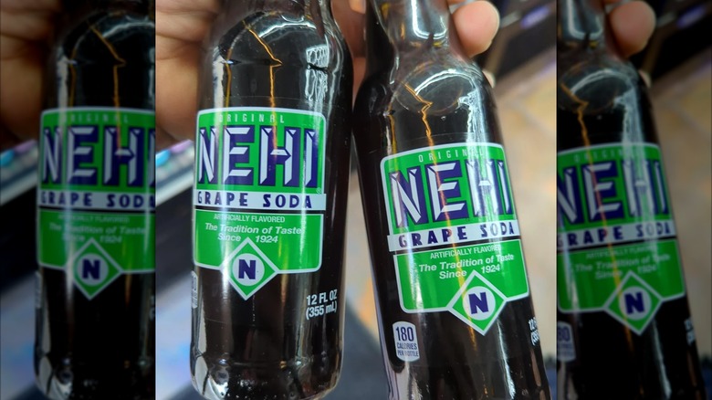 Hand holding bottles of grape Nehi soda in a store