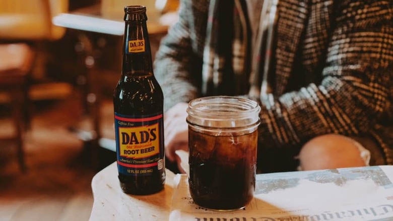 Bottle and glass of Dad's Root Beer on a table with a newspaper