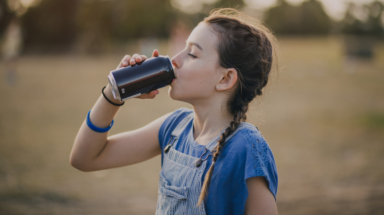 Girl outside drinking from an unmarked can of soda